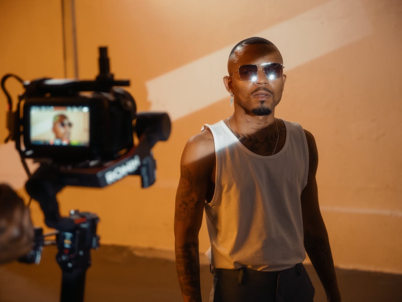 Young Man Wearing Sunglasses Posing in Front of a Movie Camera